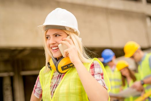 Beautiful young female construction architects using phone at a construction site.