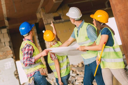 Four construction architects review plan in front building damaged in the disaster.