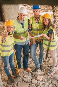 Four construction architects review plan in building damaged in the disaster.