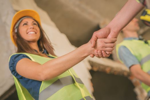 Close-up of a shaking hands of a construction workers in building damaged in the disaster. Selective focus. 