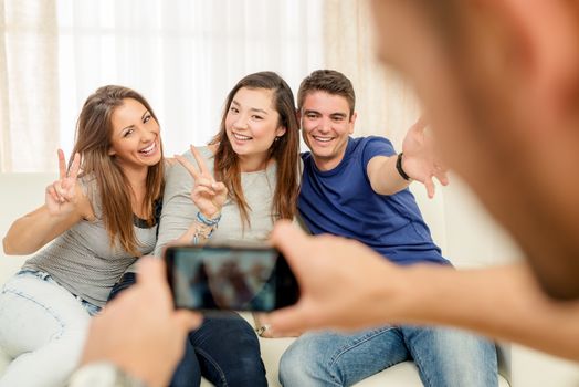 Four cheerful best friends having nice time in an apartment and taking a photo of themselves.