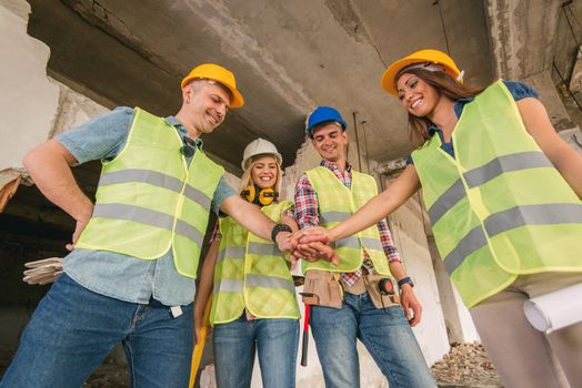 Four construction architects in building damaged in the disaster with folded hands, motivating for new business wins.