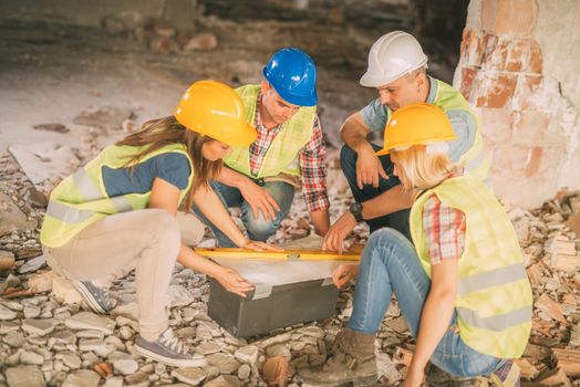 Four construction architects review plan in front building damaged in the disaster.