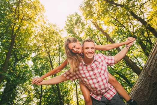 Beautiful young couple enjoying a piggyback in the forest.