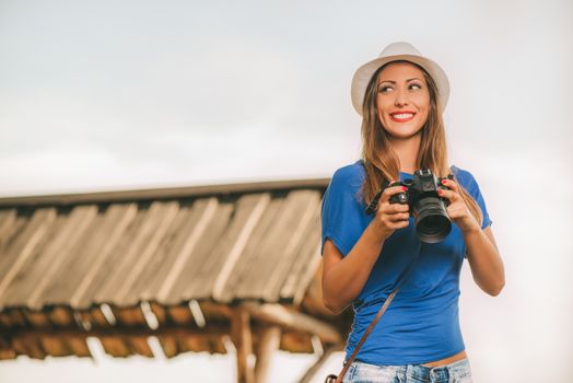 Young beautiful woman standing by viewpoint and holding digital camera.
