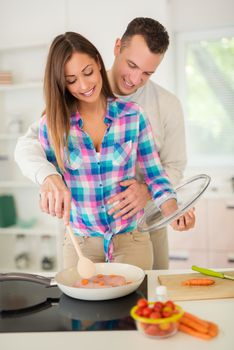 Beautiful young couple cooking healthy meal in the domestic kitchen. 