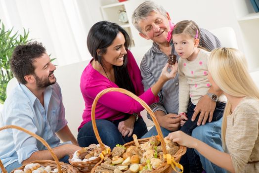 Happy family in their home eating pastries from beautifully decorated woven baskets that are on the table in front of them.