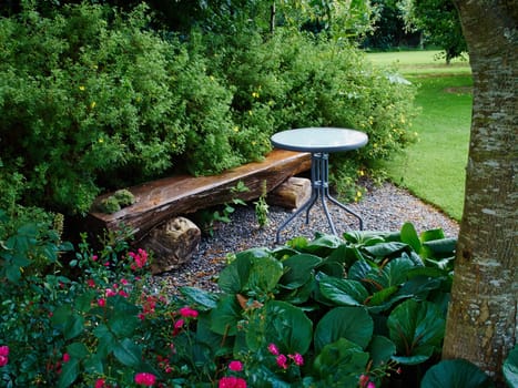 Beautiful creative wooden bench in a lush green blooming garden