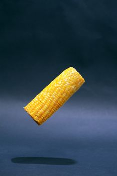 Cooking concept. Corn cob flying against nice dark background