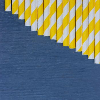 Striped straws for cocktails on blue wooden background