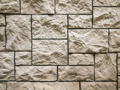 a wall from an artificial gray stone facade with rough fractured surfaces
