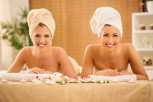 Two cute young women enjoying during a skin care treatment at a spa. Looking at camera.