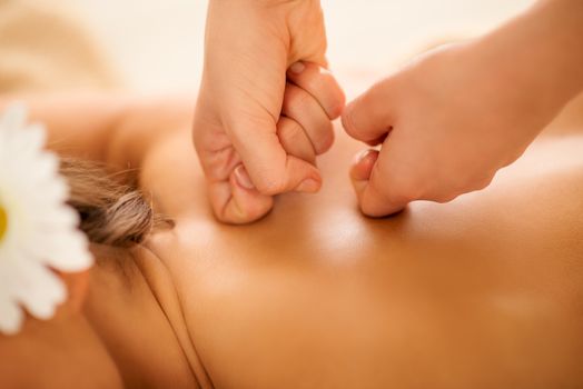 Close-up of young woman enjoying during a back massage at a spa. 