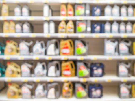 Blurred colorful motor oil bottles on shelves in supermarket as background