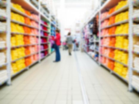 Abstract blurred supermarket aisle with colorful shelves and unrecognizable customers as background