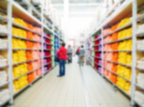 Abstract blurred supermarket aisle with colorful shelves and unrecognizable customers as background