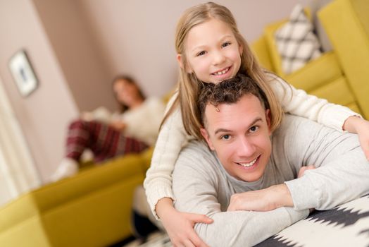 Beautiful smiling father and daughter having fun at living room and looking at camera.