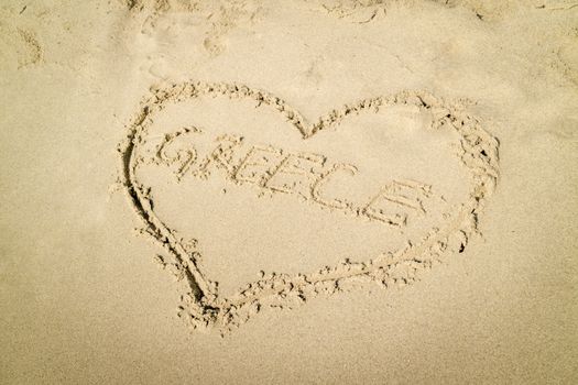 Heart shaped word Greece written on the sandy beach.