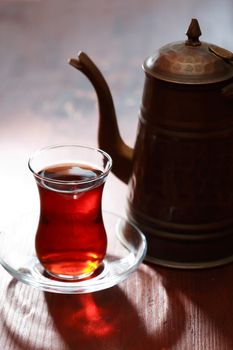 Cup of Turkish tea near teapot on wooden table