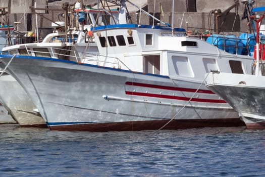 Some colorful fishing boats are anchored in the harbor of Acireale, Sicily-Italy on the coast of the Mediterranean Sea.