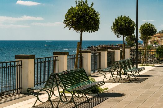 Bench and little trees at the sicilian sea, Italy.