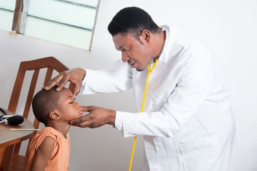 The health professional examines the boy looking in his eye.