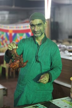 A cook holds a delicious tandoori chicken during the ramadan feast in India