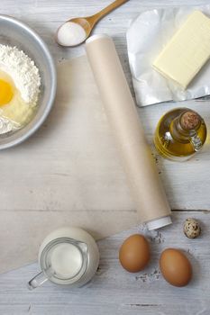 Ingredients for the pancakes on the white wooden table around the parchment roll 