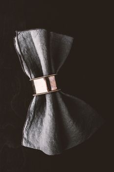 Grey napkin in the vintage metal ring on the black wooden table