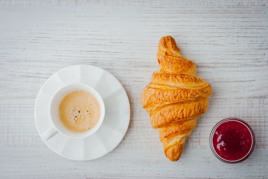 Cup of coffee with croissant and jam top view