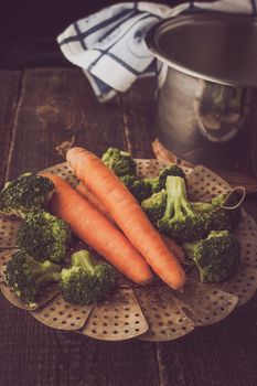 Steamed carrots and broccoli on the wooden table