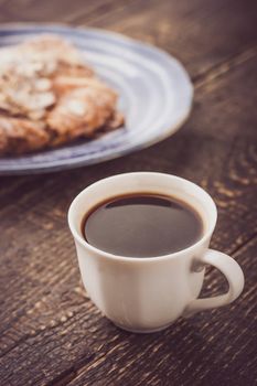 Cup of coffee with blurred croissant   on the blue ceramic plate vertical