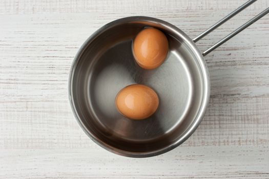 Eggs in water in a metal pan top view