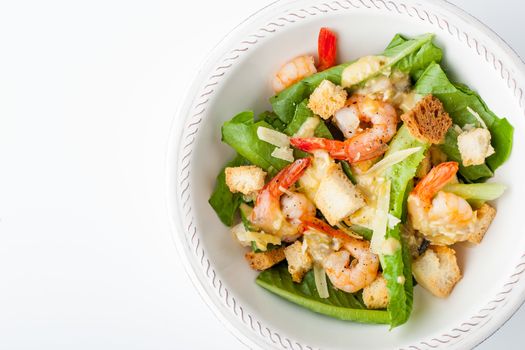 Caesar salad with shrimps on the white background top view
