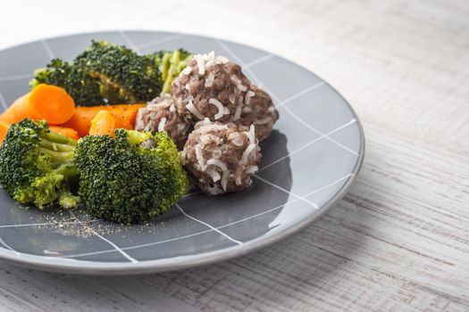 Steamed vegetables with meatballs on the gray plate