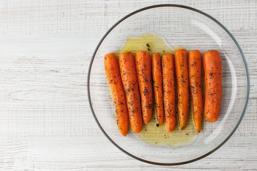 Baked carrots with black pepper on the glass plate top view