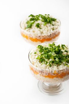 Layered salad with eggs and fish on the glass dish vertical