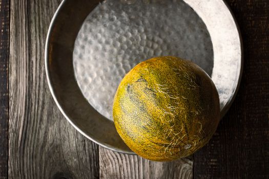 Melon in the metal plate  on the wooden table horizontal top view