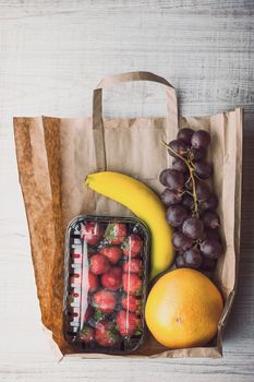 Strawberry with different fruit inside a paper bag vertical