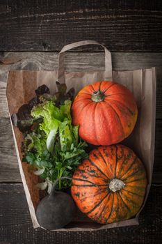 Pumpkins and vegetables inside a paper bag vertical