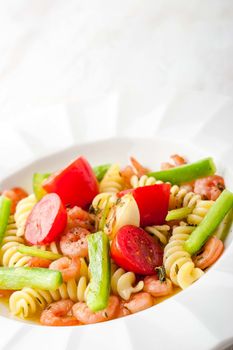 Pasta with vegetables and prawns on the white background vertical