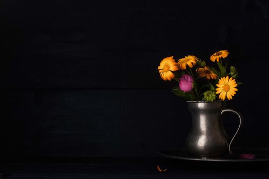 Bouquet of flowers in the old metal jug horizontal