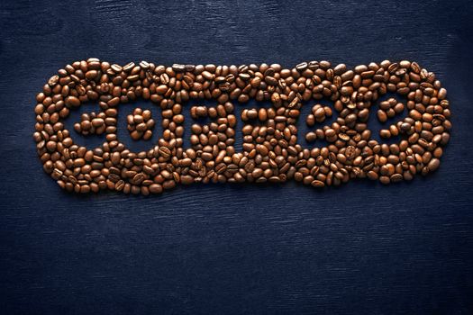 Inscription of coffee from coffee beans on the dark background