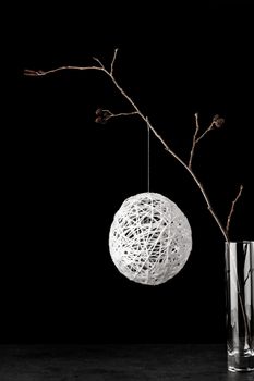 Alder branch in the glass with a white christmas ball on the black stone table vertical 