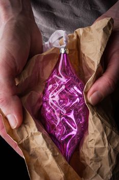Christmas tree decoration in wrapping paper in the hands vertical