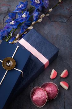 Spring gift with candy and flowers on a blue stone background vertical