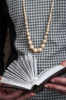 A woman in a Chanel-style reading a book vertical