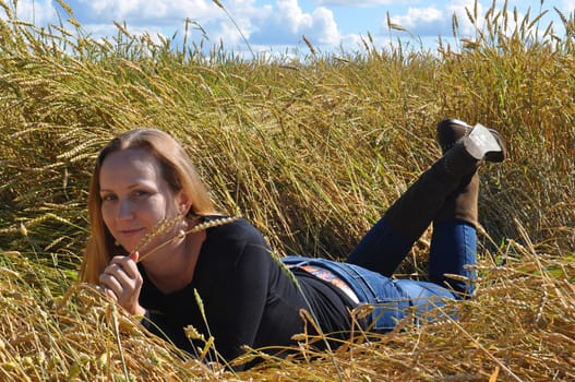 the beautiful woman lies in a wheat field