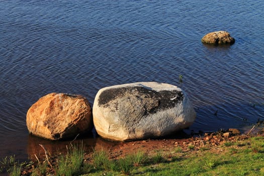 Stones and Pond - Three large stones in a pond with water ripples