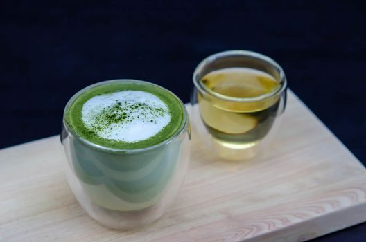 closeup cup of green tea latte on wooden plate